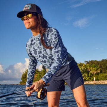 Angler in sun protection gear casts line.