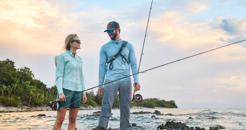 Two anglers smiling in conversation standing in the ocean.
