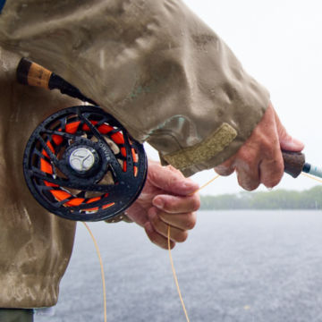An angler holds his rod with a Mirage reel as he casts into the rain.