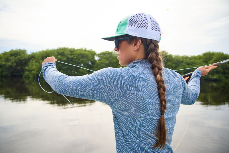 An angler wearing UPF clothing, hat, and sunglasses.