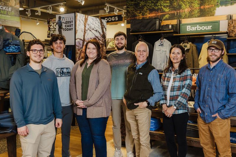 A group of Orvis employees smile together in the Orvis Hunterville Store.