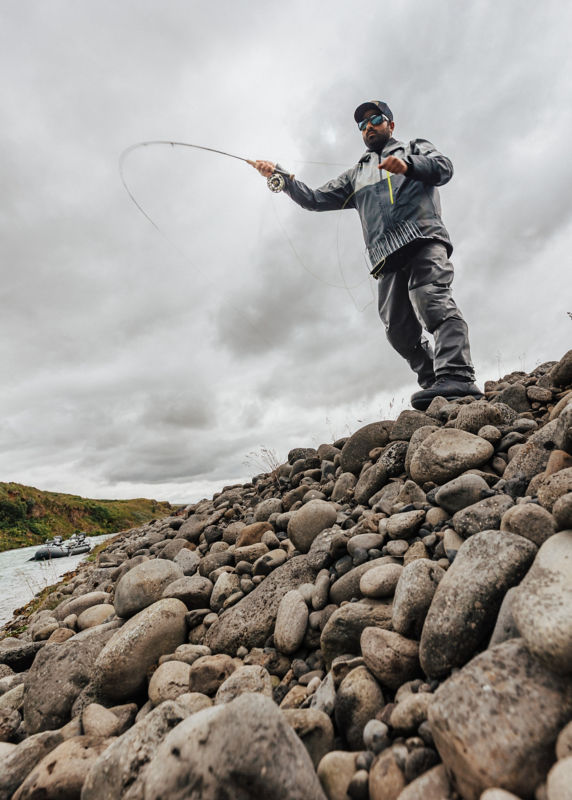 A view from below a stone embankment of an angler casting.