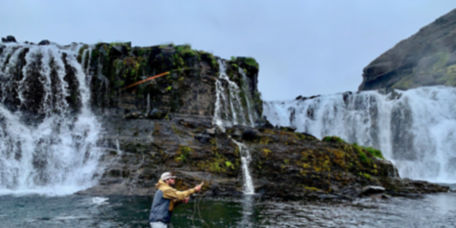 An angler casts a fly rod surrounded by waterfalls in Iceland