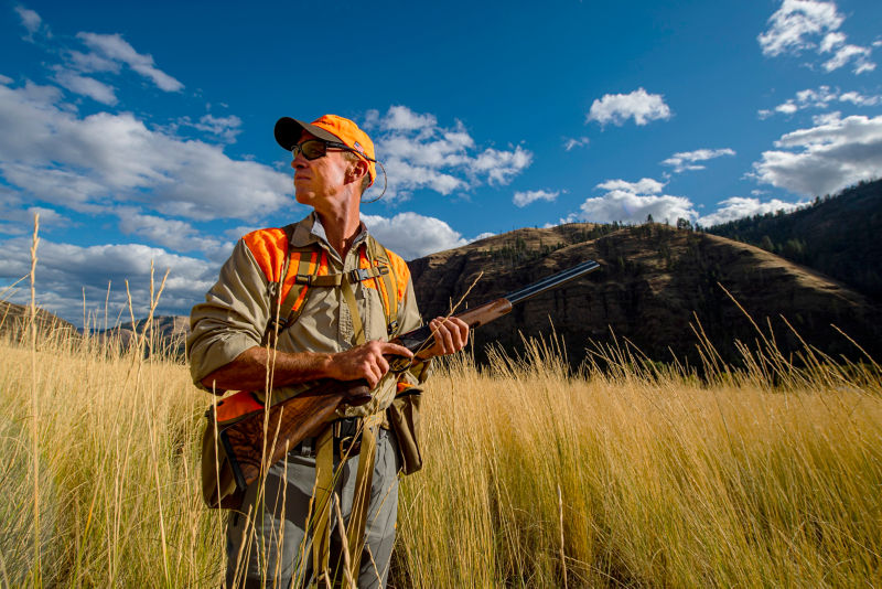 A hunter, scanning the endless landscape at Flying B Ranch in Idaho in a Long-Sleeved Featherweight Shooting Shirt
