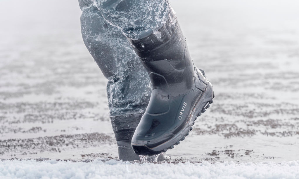 An angler in Orvis Bootfoot Waders picks their way through ice and water.