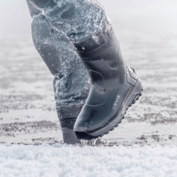 A close-up of a person wearing winter boots walking through the snow