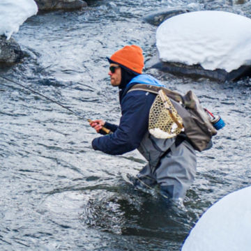 Man wading in icy river watches as his fly line comes back to him.