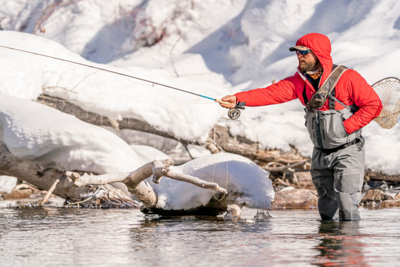 Man casts rod as he wades in freezing waters inside his PRO Zip Bootfoot Waders.