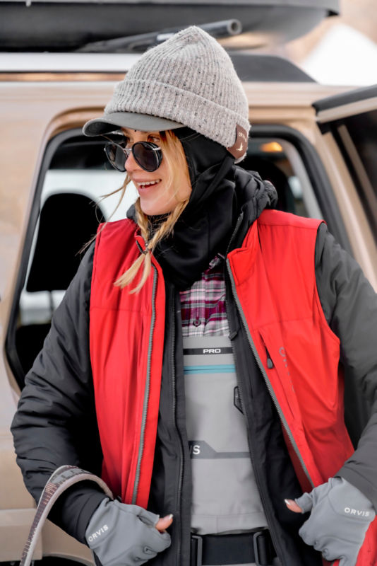 An angler zips up cold weather gear over her waders.