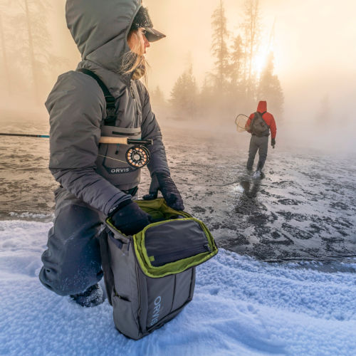 Two anglers set up to fish on a snowy, misty morning.