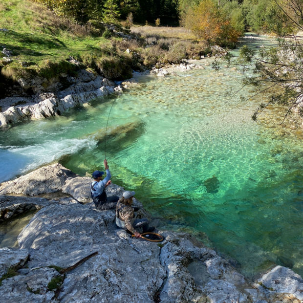 An aerial shot of a person fly fishing in pristine waters.