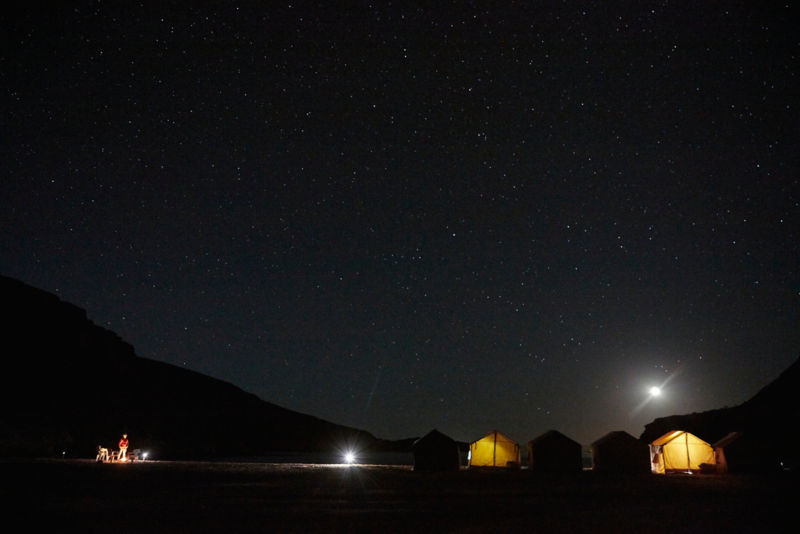 A gorgeous starry night with tents lit up inside.