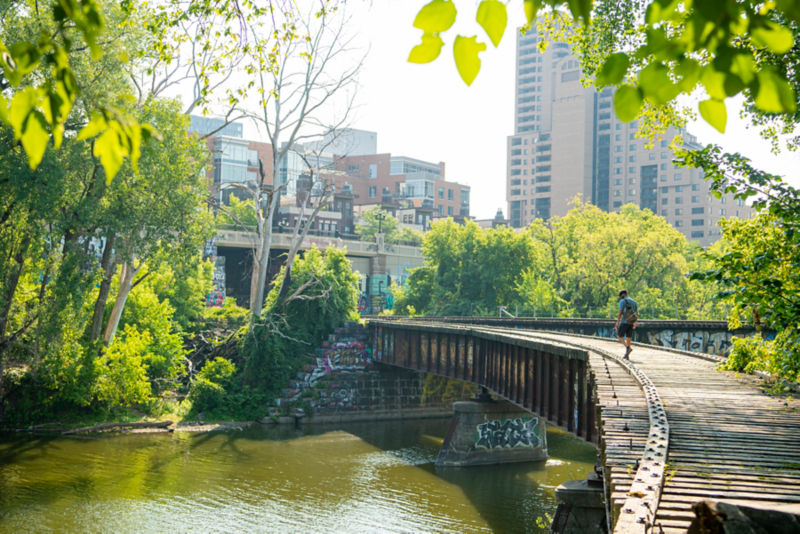 An angler walking across the railroad bridge, with the city buildings in the background