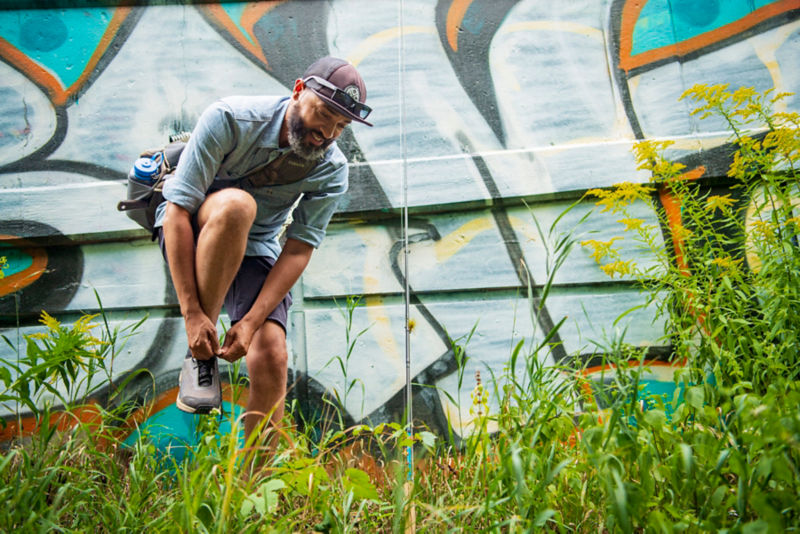 An angler balances on one foot while tying their shoe.