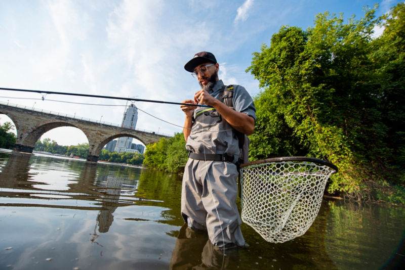 Ashley White in full fly-fishing gear, fishing in an urban setting