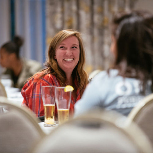 A woman at a table smiles for the photographer