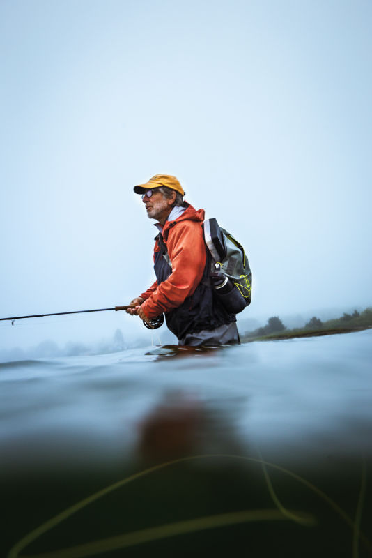 Tom Rosenbauer fishes while wading waist-deep in the river.