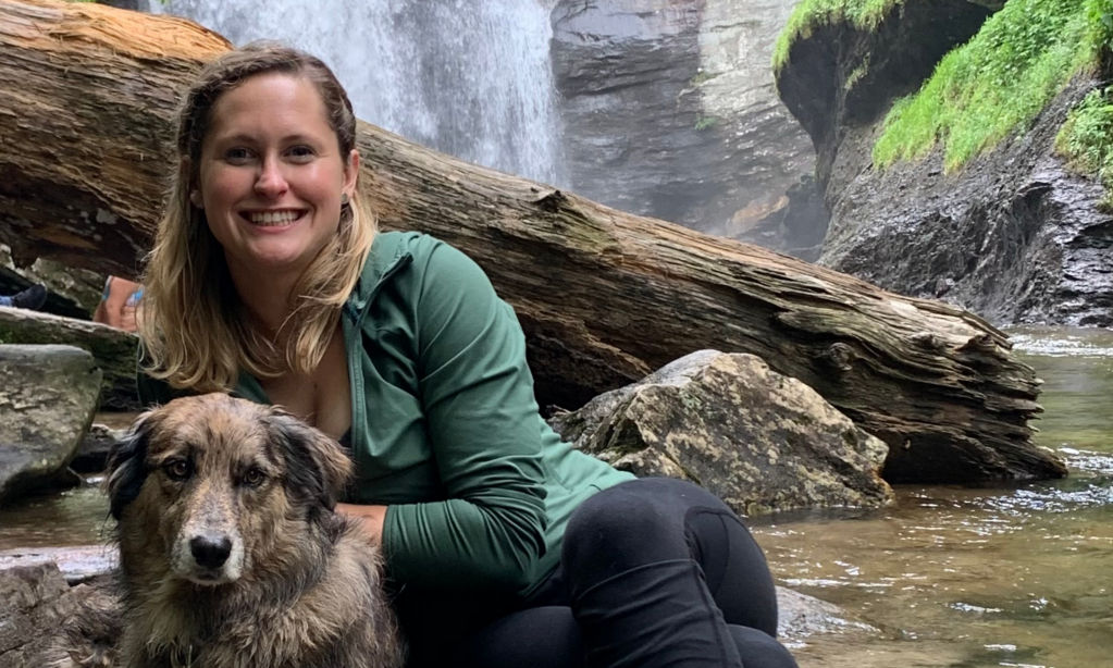 A portrait of product developer Marina Kozera and her dog with a waterfall background.