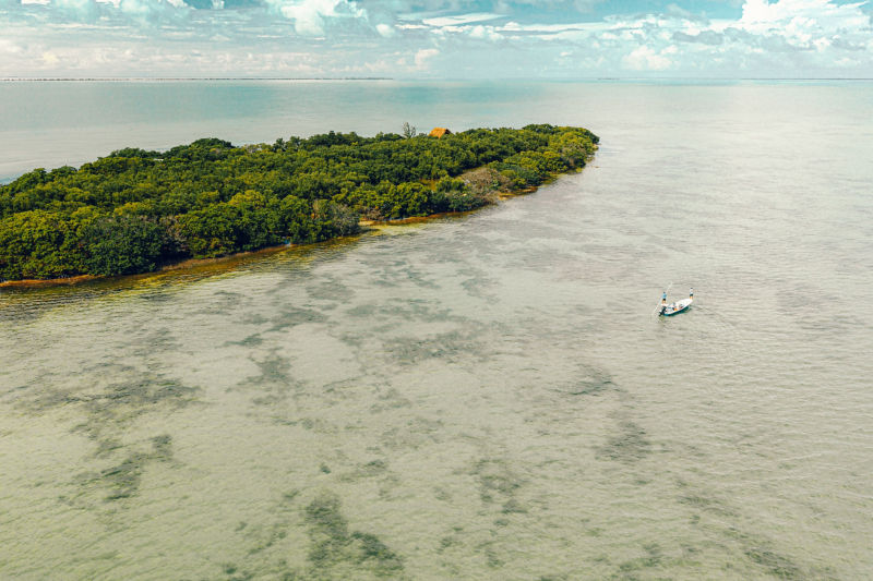 Three people fly fishing from a boat in El Pescador, Belize.