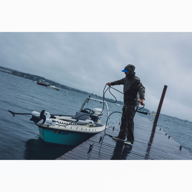 An angler in full winter gear ties a boat up to a dock