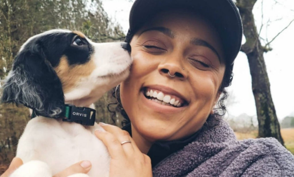 A smiling Melinda Benbow holding her white, black, and brown dog near her face
