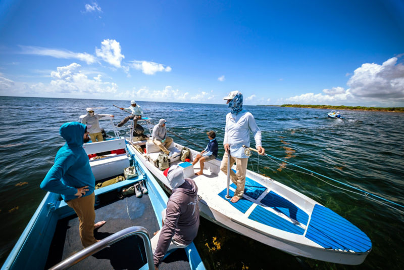 A group of anglers on a two boats side by side in the ocean.