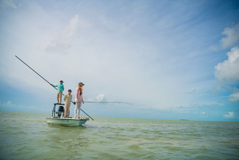 Three anglers fishing the flats from a poled boat.
