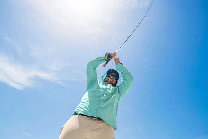 Shot from below, an angler grits his teeth while hauling a fish in.