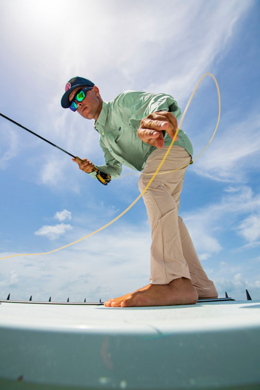 A shot from below of an angler on a boat deck working his line.