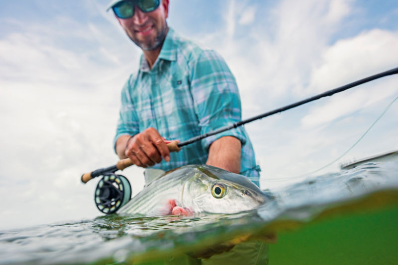 An angler carefully holds a caught fish on the surface of the ocean.