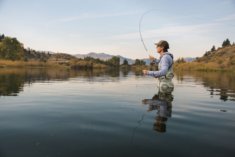 An angler standing in a river casting a fly rod.