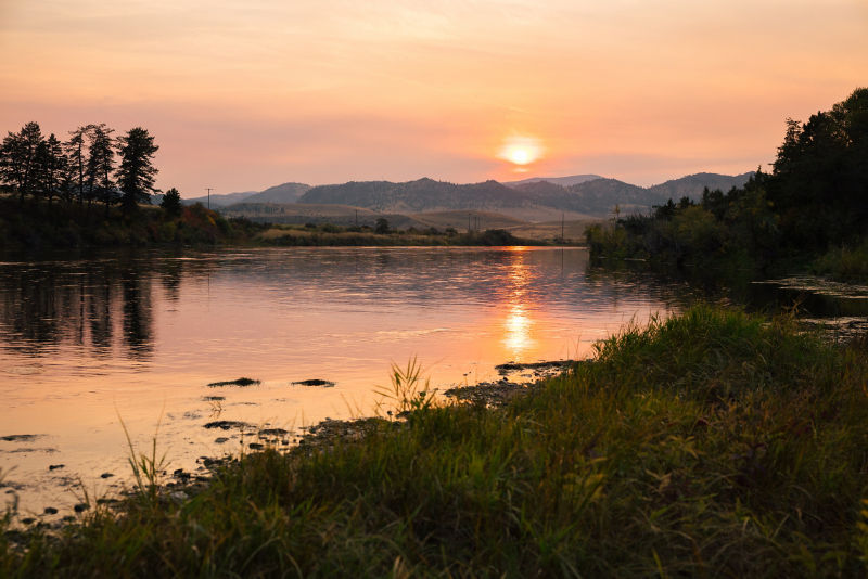 Sunset over the mountains reflects into the river below.
