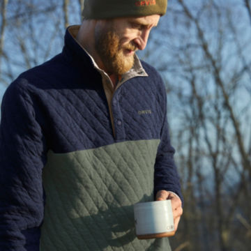 Man in Navy/Juniper Outdoor Quilted Snap Sweatshirt drinks his coffee outdoors.