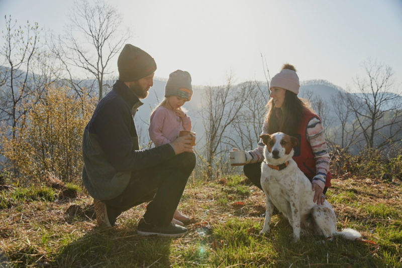 A family and their dog in the early morning with mountains and fog as the backdrop