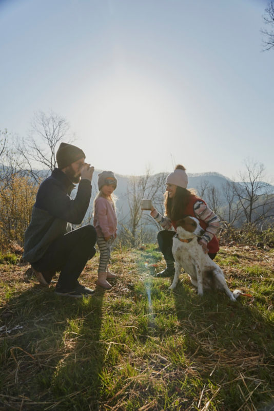 Two parents and a small child with a dog on an outdoor morning.