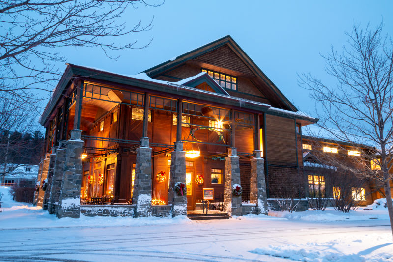 The lit up exterior of the Orvis Flagship Store at dusk surrounded by snow.