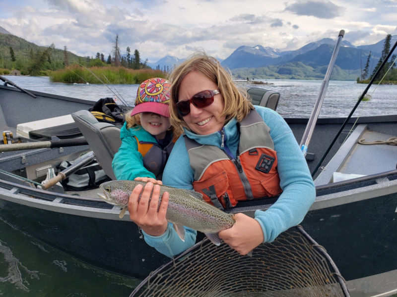 An angler shows off her catch with her child watching over her shulder.