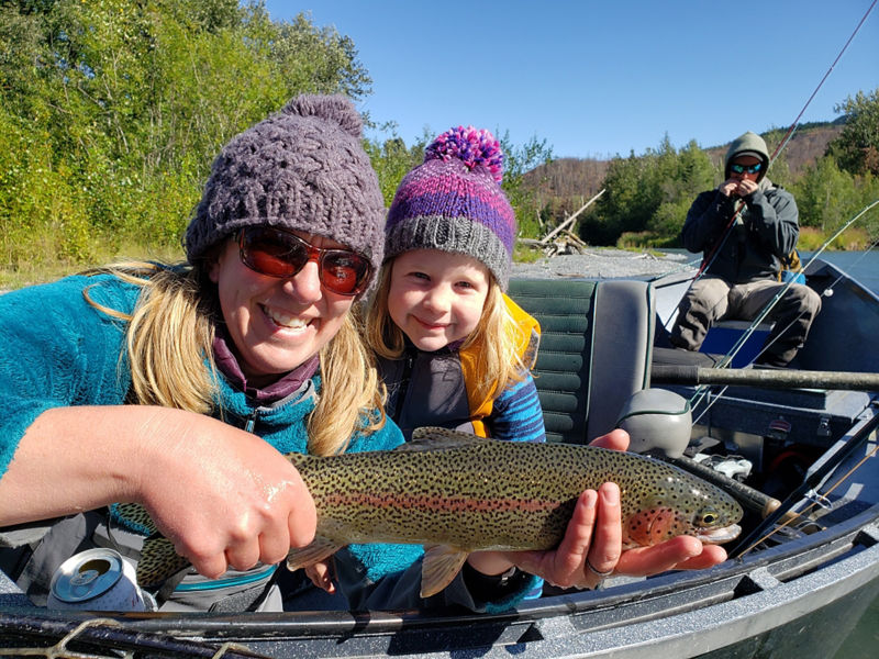 A woman and child smile as they show off a freshly-caught fish.