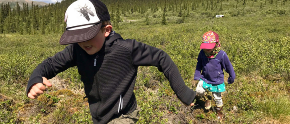 Two children run through scrublands in Alaska.
