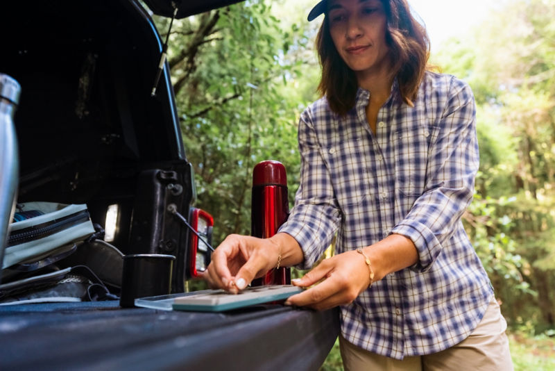 A woman in a plaid button-down stands choosing a fly from her fly box.