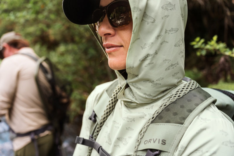 An angler wearing a sage green sun protective hoodie with sunglasses.