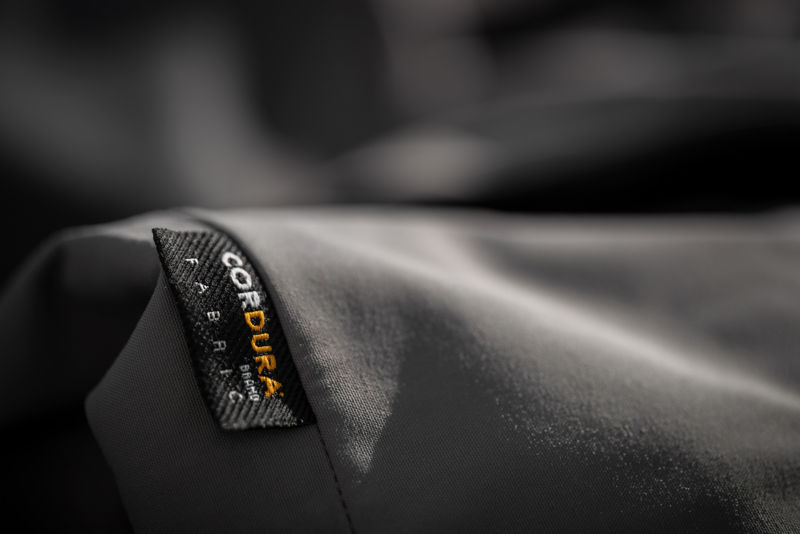 A close-up of the CORDURA Fabric tag attached to gray cloth