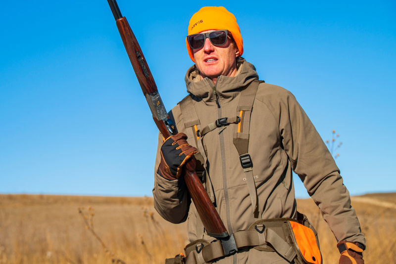 Man in Pro HD Softshell hoodie walks through a field