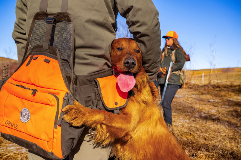 A hunter hugging his golden retriever.