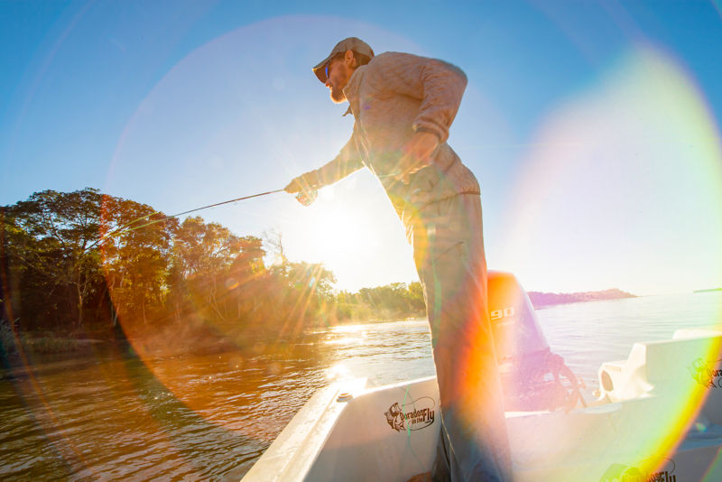 An angler casts off a boat at sunset.