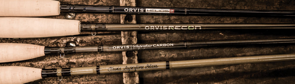 Four Orvis fly rods sit on a wooden background.