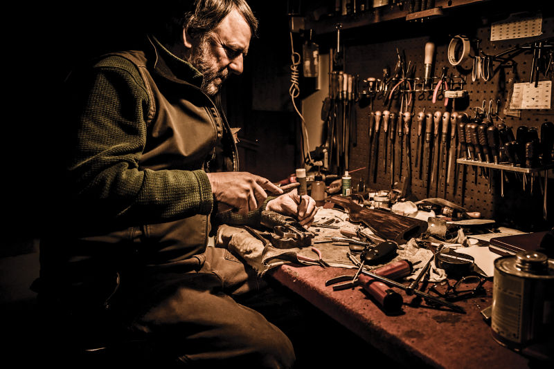 A man tunes up a reel at a workbench filled with tools.