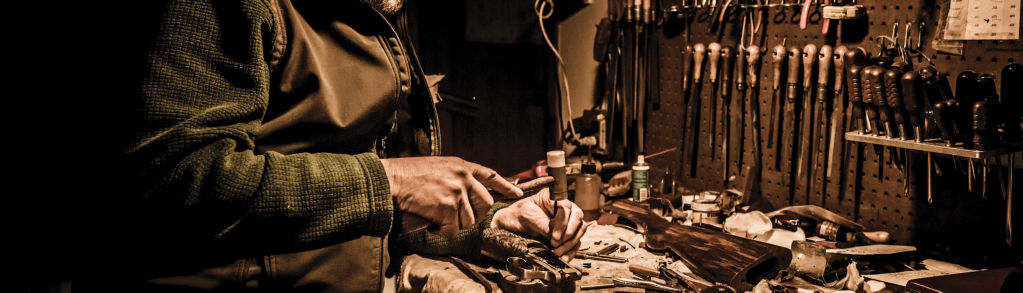 A gunsmith at his workbench repairing a shotgun.