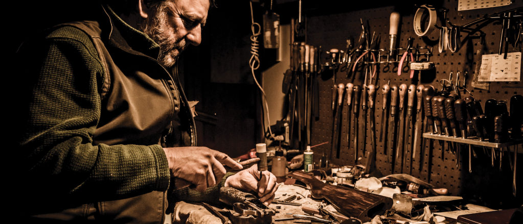 An Orvis Gun Smith sits at his workbench surrounded by tools