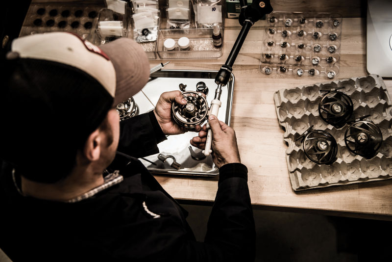 Looking over a man's shoulder as he tunes up a fly reel.
